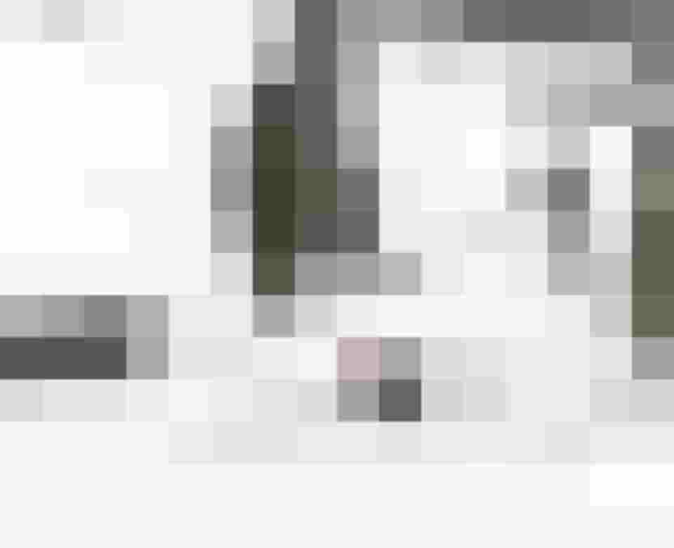 Schneebedeckte Landschaft mit einer Pferdeschlittenfahrt vor rustikalen Waldhütten.